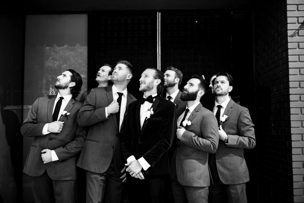 It is a black and white photo of the groom and the groomsmen, looking up at the sky.