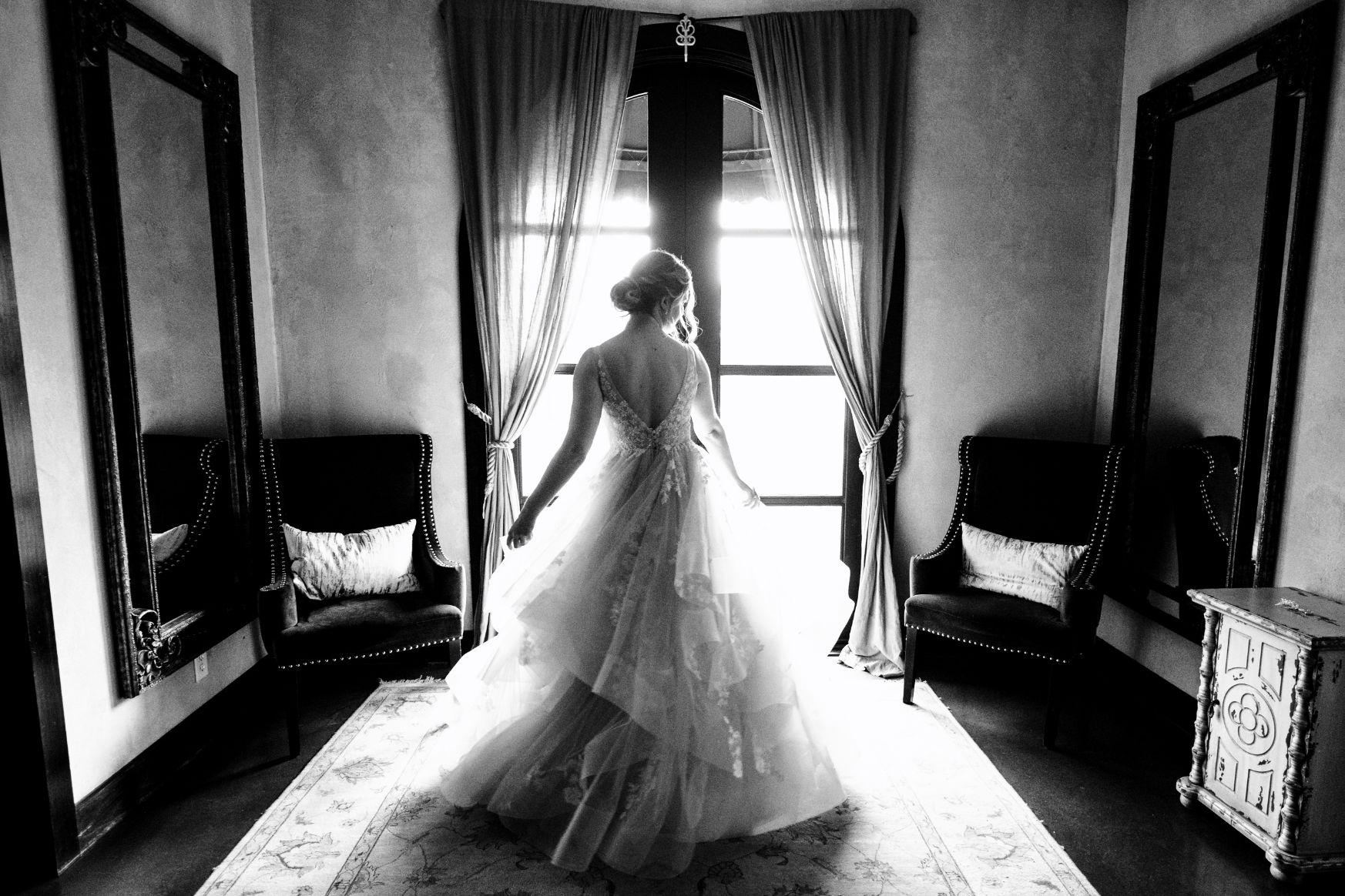 Black and white style image with bride twirling around with wedding dress.