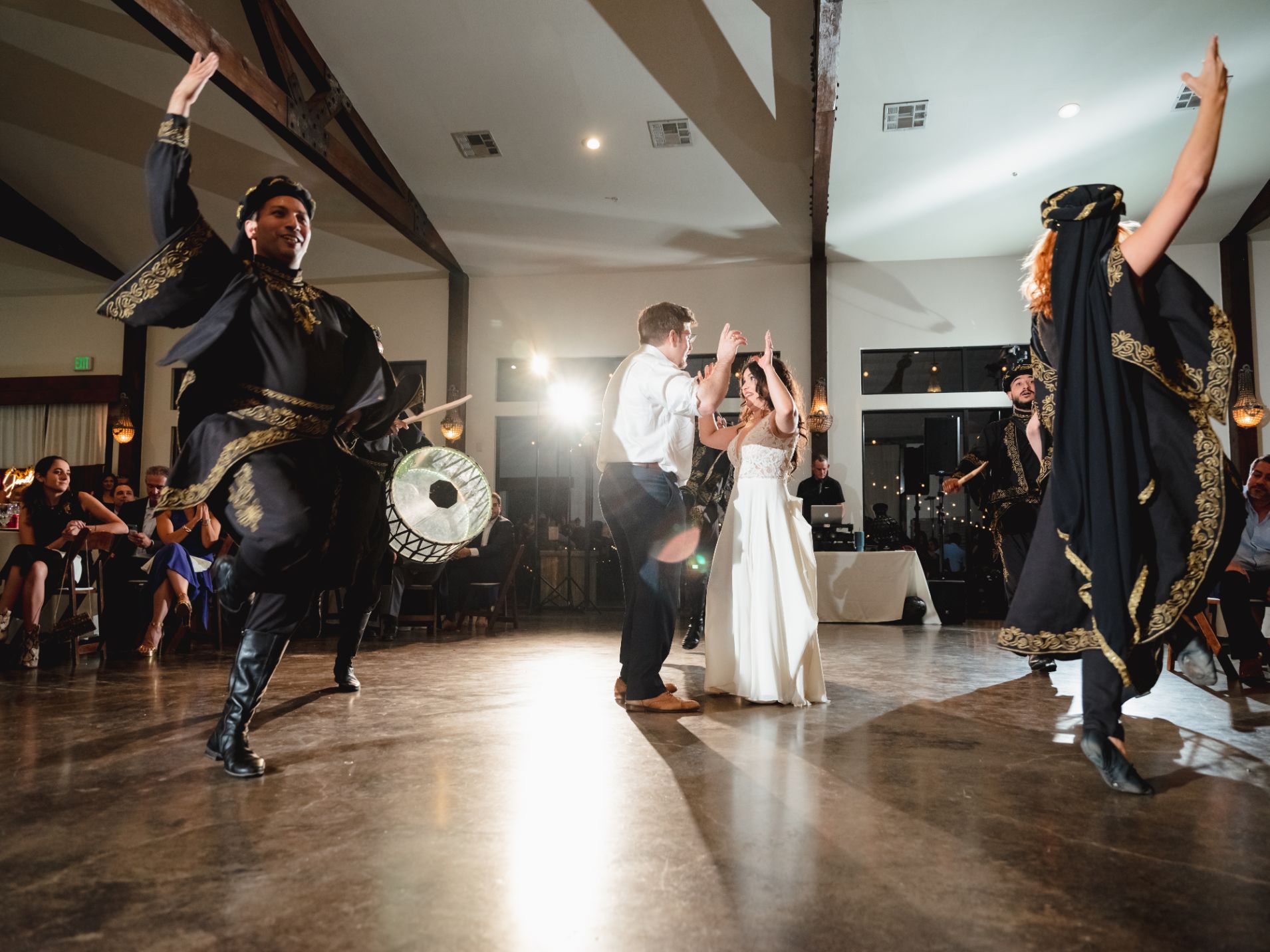 Bride and groom dance as professional dancers with drums dance and play music around them during a wedding reception.