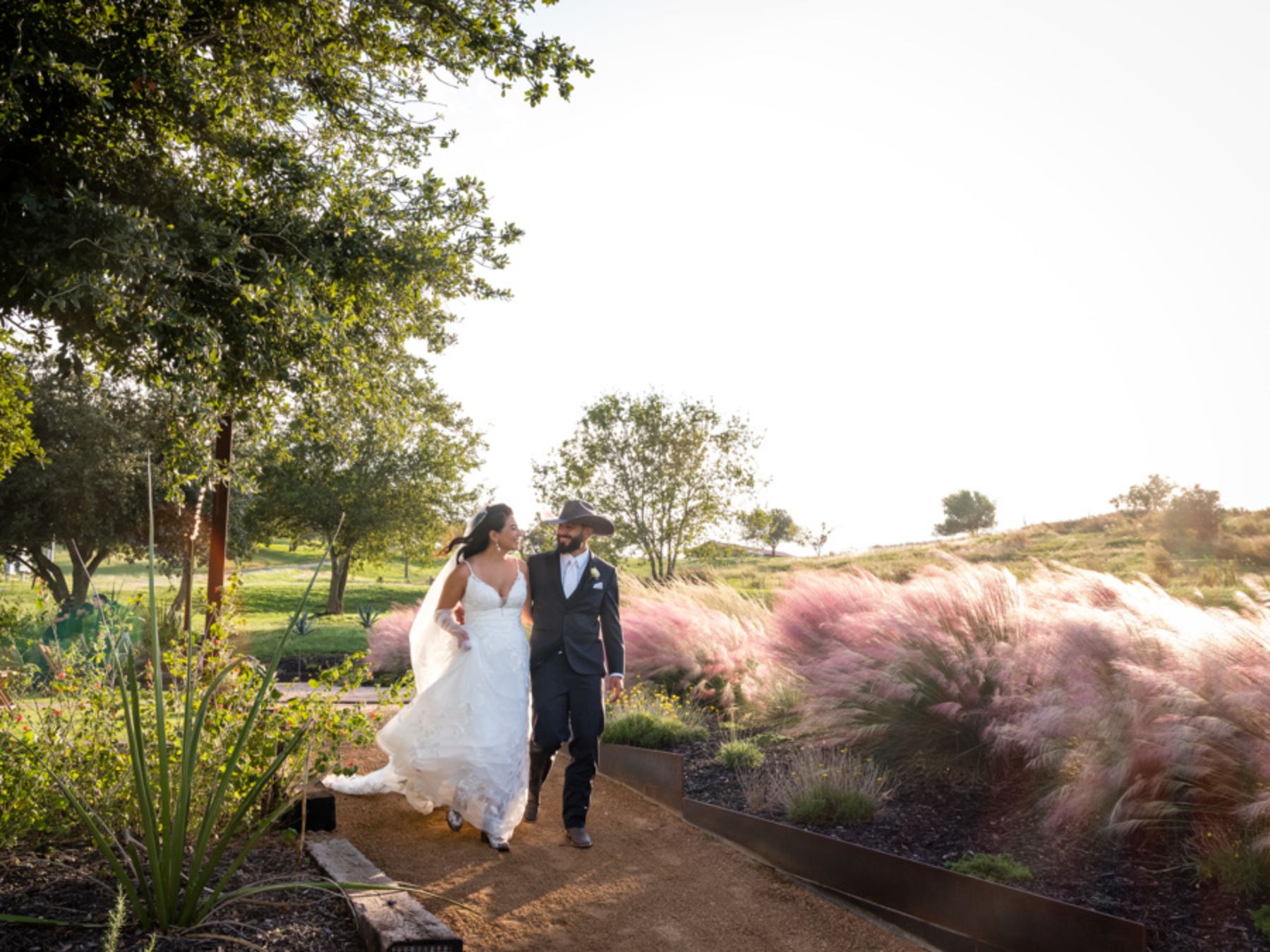 Bride and groom walking on outdoor pathway during wedding at Two Wishes Ranch in Austin Texas.