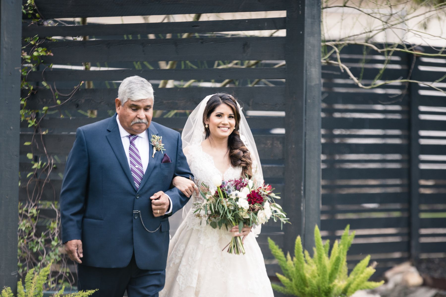 Bride walks hand-in-hand, with father down the aisle of her outdoor wedding ceremony at Stonehouse Villa