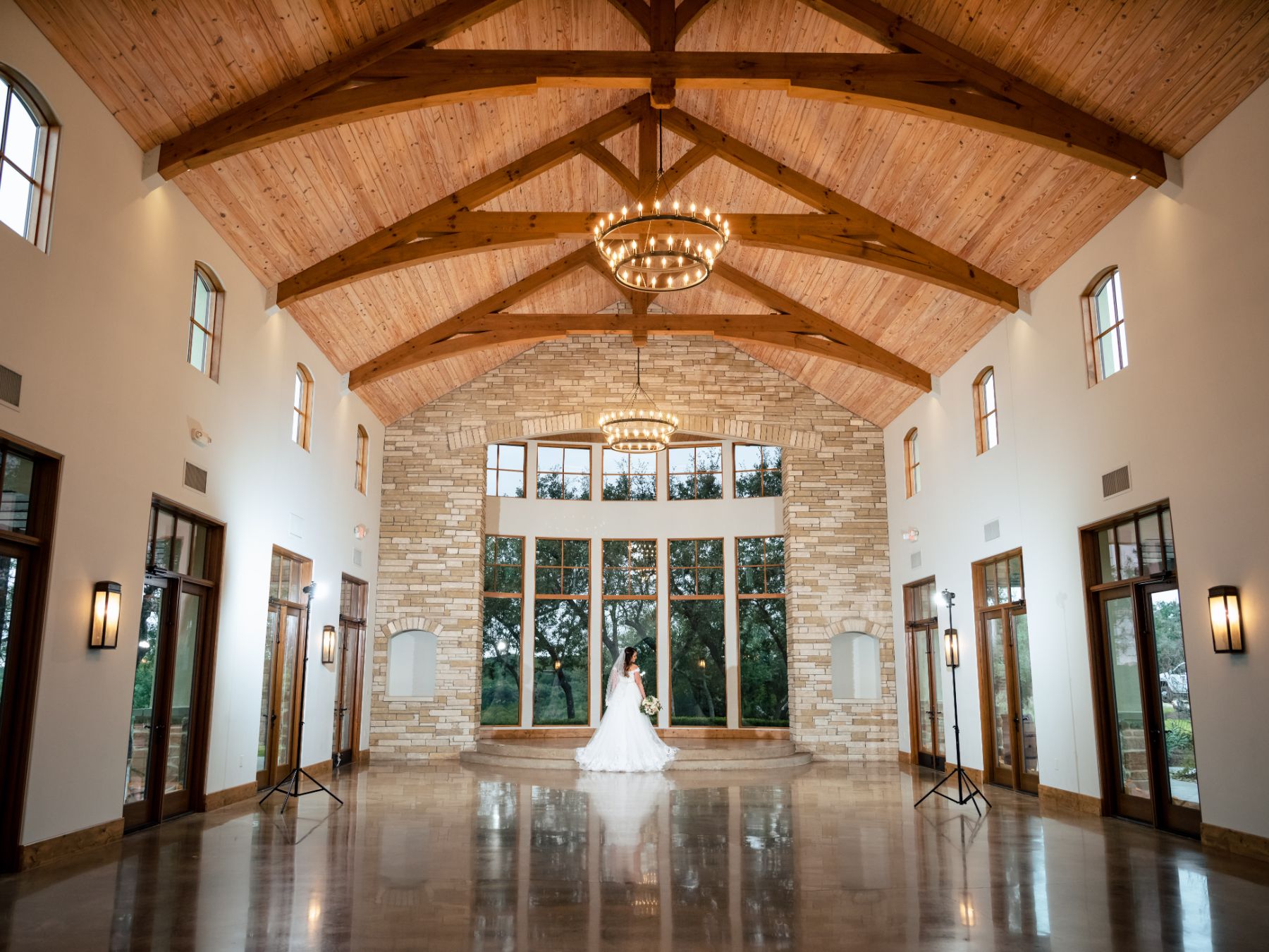 Fried poses inside Canyonwood Ridge wedding chapel with exposed wood beams, and a stone wall
