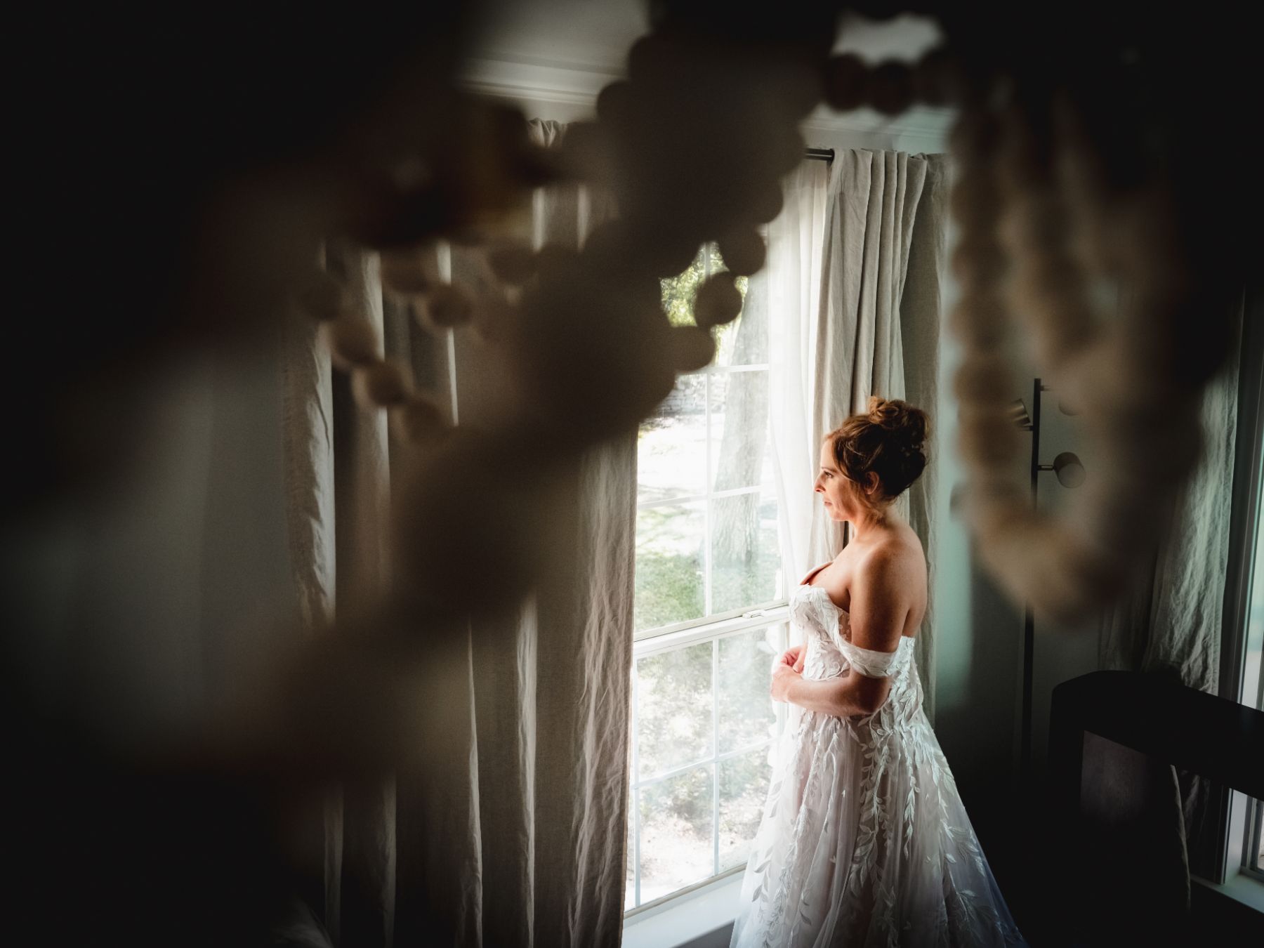 I ate bride, looks out a window before her wedding ceremony.