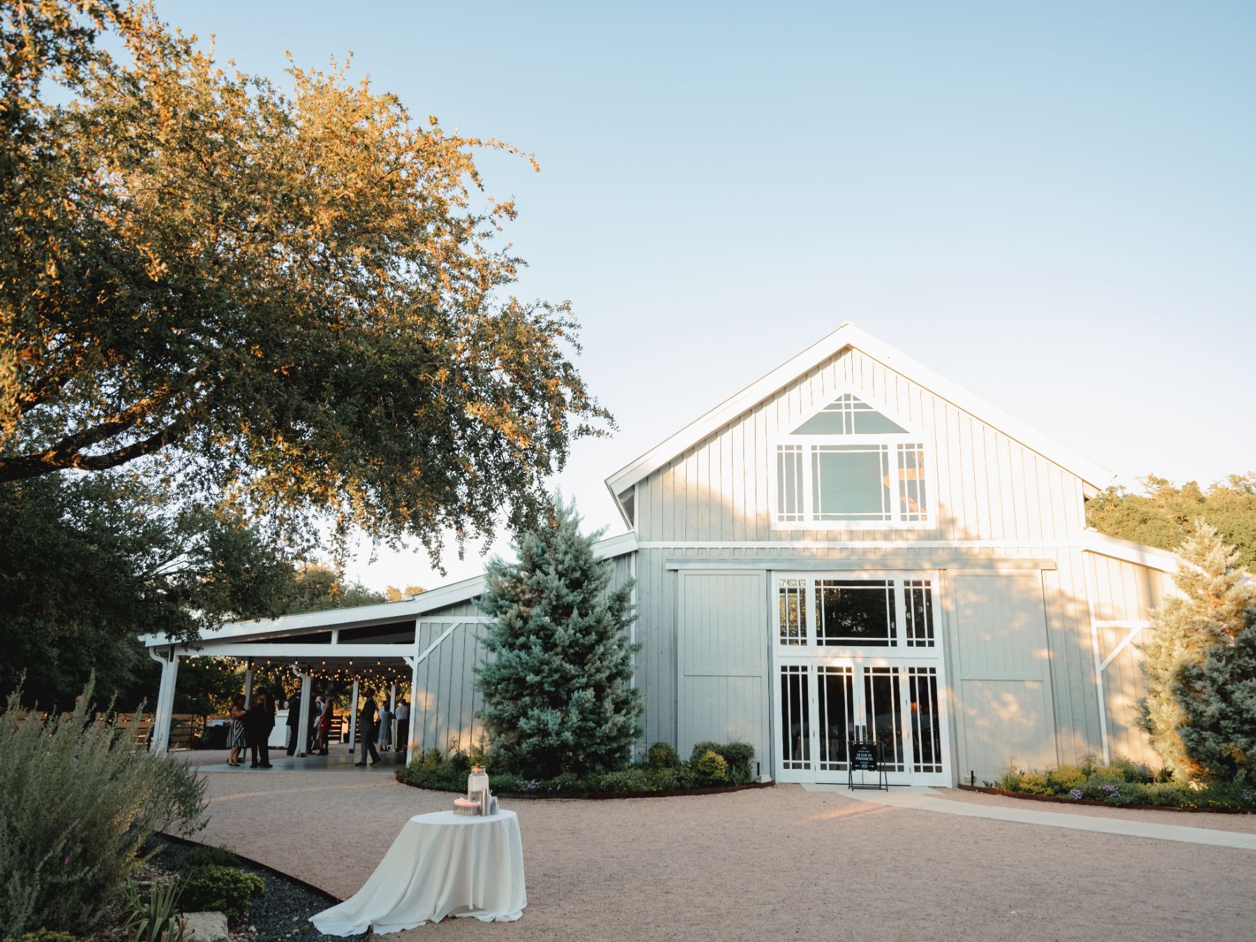 Beautiful large gray barn, surrounded by natural scenery and large trees at The Addison Grove wedding venue in Austin Texas.