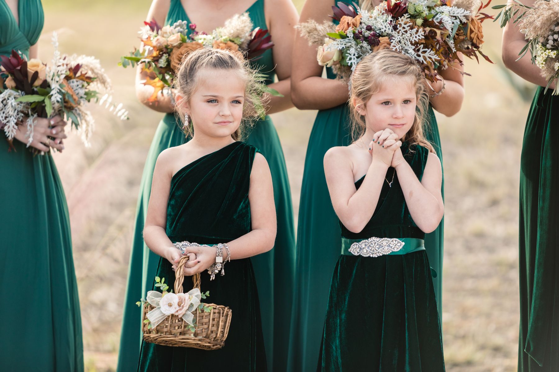 Flower girls in green velvet dresses stand near bridesmaids.