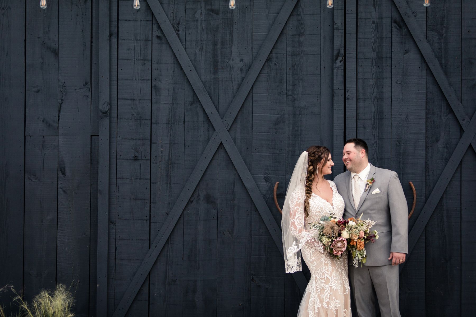 Bride and groom stand near a black barn during wedding at Two Wishes Ranch in Austin Texas.
